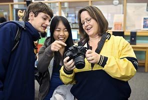 Laura Martin says she's found that at diverse Mercer Middle, her daughters are "engaged and challenged." Here, she looks over photos with Mercer students Jesse Senior, left, and Vy Tran.
