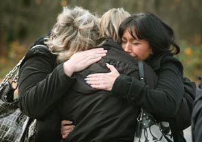 Three women embrace in front of a memorial in front of the Lakewood Police Department Monday morning.  Officers and members of the public brought flowers, cards and teddy bears and placed them in front of the Lakewood Police Department in honor of the four slain police officers who were killed in a Parkwood coffee shop Sunday morning.. 