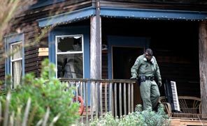 An officer wearing a gas mask exits the East Superior Street home in Seattle's Leschi neighborhood. Police staked out the home all night. 