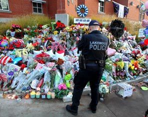 A Lakewood police officer pauses Tuesday morning in front of a memorial set up outside the Lakewood Police Department to honor the four officers who were killed on Sunday. Another public memorial, with piles of bouquets, formed near the coffee shop where they were shot. 
