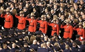 Royal Canadian Mounted Police officers salute as the caskets of the four slain Lakewood officers are taken from the Tacoma Dome. 
