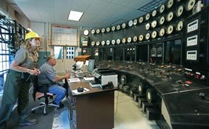Park Ranger Denison Rauw stands behind Kevin Yancy, the last project manager for the Elwha hydroelectric project. With brass and glass dials set in black slate supported by steel Doric columns, the dam's control panel was a signature of a grand industrial age. 