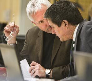 Dr. Jeff Thompson, left, chief medical officer for state Medicaid, confers with Duane Thurman, a program manager with the state's Health Care Authority, during a meeting of the panel authorizing the advisory. 