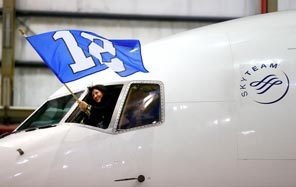 A member of the crew aboard a chartered Delta Boeing 767-300 carrying the Seattle Seahawks waves the 12th Man flag as it taxied into a hangar at Newark Liberty International Airport on Sunday.