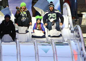 Jon Cook, right, and his wife, Ryanna Cook, try out the toboggan with their daughter, Aiyanna, 4, on Super Bowl Boulevard in New York City on Thursday. The family is from Lake Stevens. Toboggan riding is one of the many activities along the section of Broadway that’s closed to cars.
