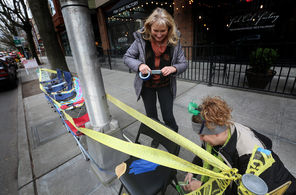 Rachel Osburn, left, of Lake Stevens, and her mother, Kathy Reed, use blue and green tape to connect chairs they set out Tuesday afternoon on Fourth Avenue near Vine Street in Seattle, near the beginning of Wednesday's parade route.