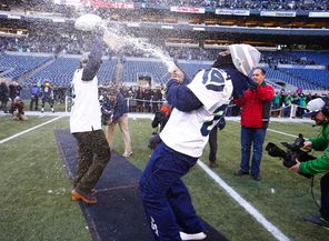 Running back Marshawn Lynch, right, pops the cork on a bottle of champagne, spraying quarterback Russell Wilson, who was holding the Lombardi Trophy.