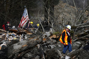 Mike Breysse, safety manager for the Washington State Department of Transportation, walks Monday in the wreckage and debris near mile marker 37 on Highway 530 in Snohomish County.