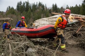 Rescue workers on Tuesday carry an inflatable boat to the flooded area in the debris field caused by the massive mudslide near Oso in Snohomish County. 