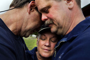 Darrington volunteer firefighters (from left) Jeff McClelland, Jan McClelland and Eric Finzimer embrace Wednesday after saying a prayer.  The three took time out from digging through debris Wednesday to talk about what it’s like to be on the front lines of a grim search. 