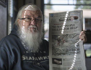 Larry Taylor holds The Seattle Times Sunday edition with the photo he took of Randy Fay rescuing Jetty Dooper. 