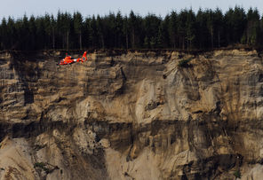 A Coast Guard search helicopter flies Monday near the cliff  left after the massive mudslide above the North Fork of the Stillaguamish River. 