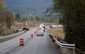 A string of cars heads east toward Darrington  last Thursday, led by a pilot car and followed by a security vehicle, on the new Highway 530 near Oso. With debris cleanup finished, crews are working to completely open the road by Tuesday. 